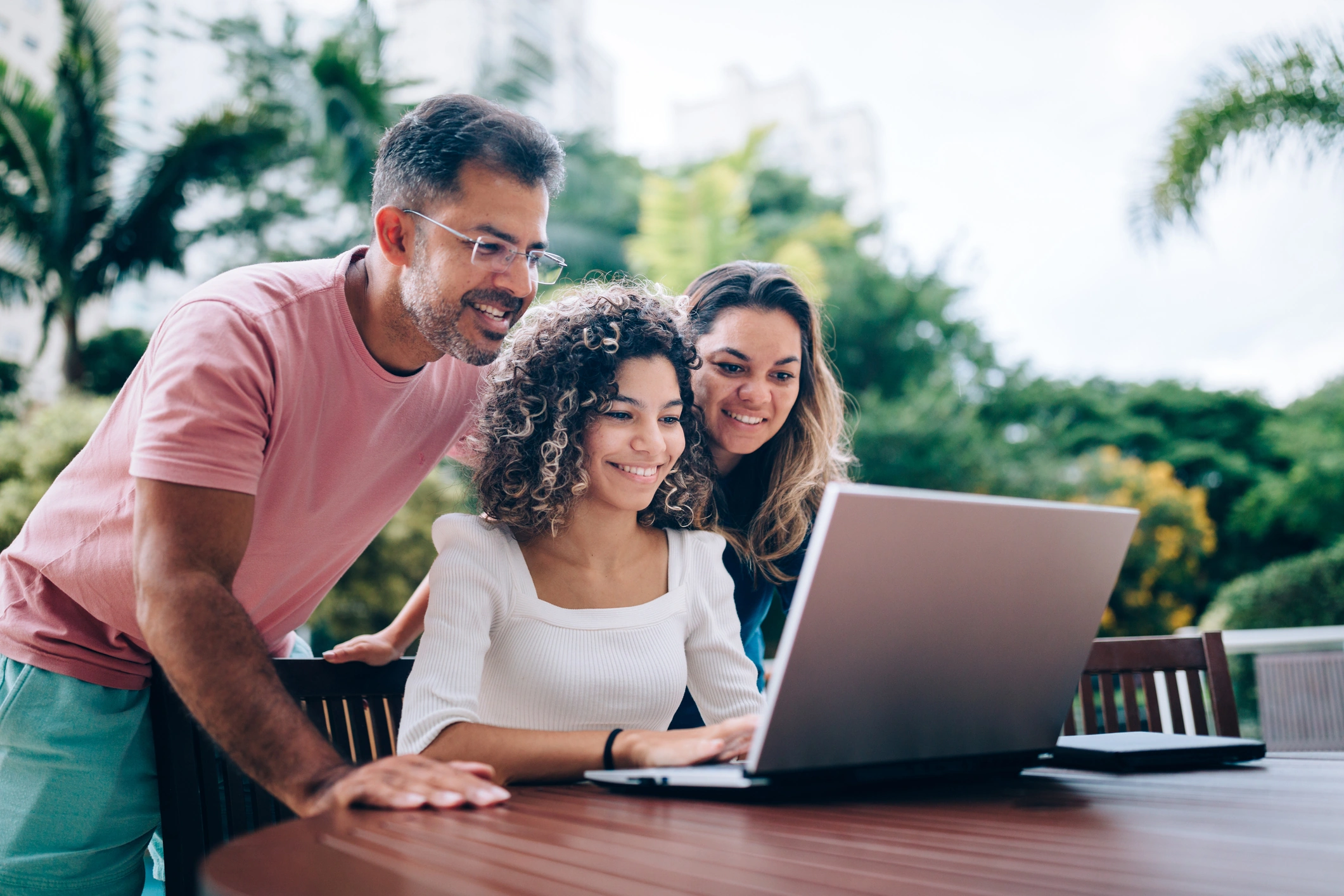 Parents around girl at laptop